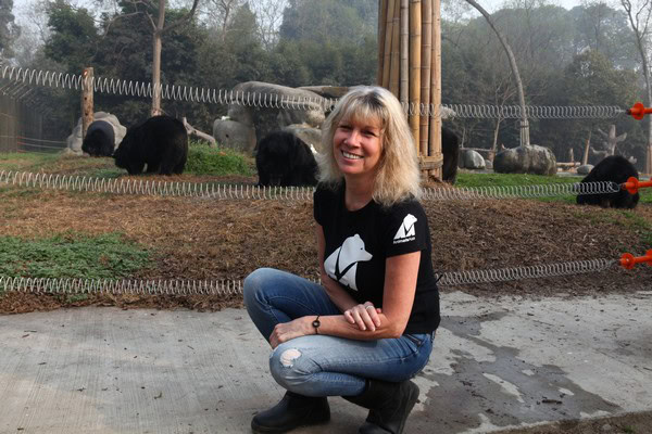 Jill Robinson crouches outside a newly established bear sanctuary, smiling.